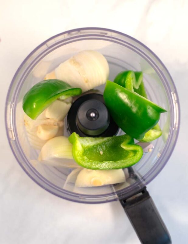 Onions, garlic, and bell pepper in a food processor before chopping.
