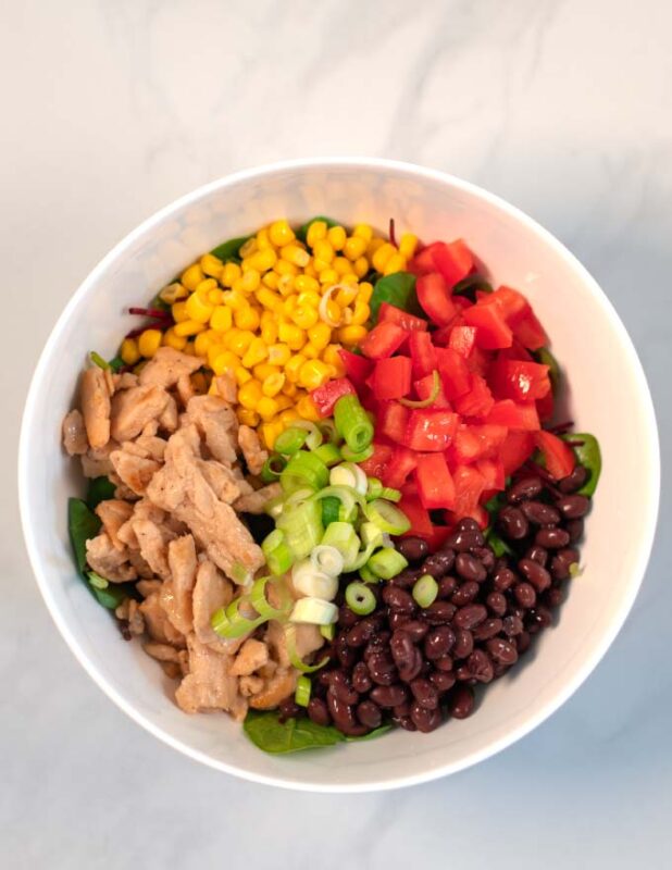 View of a white micing bowl with the salad ingredients.