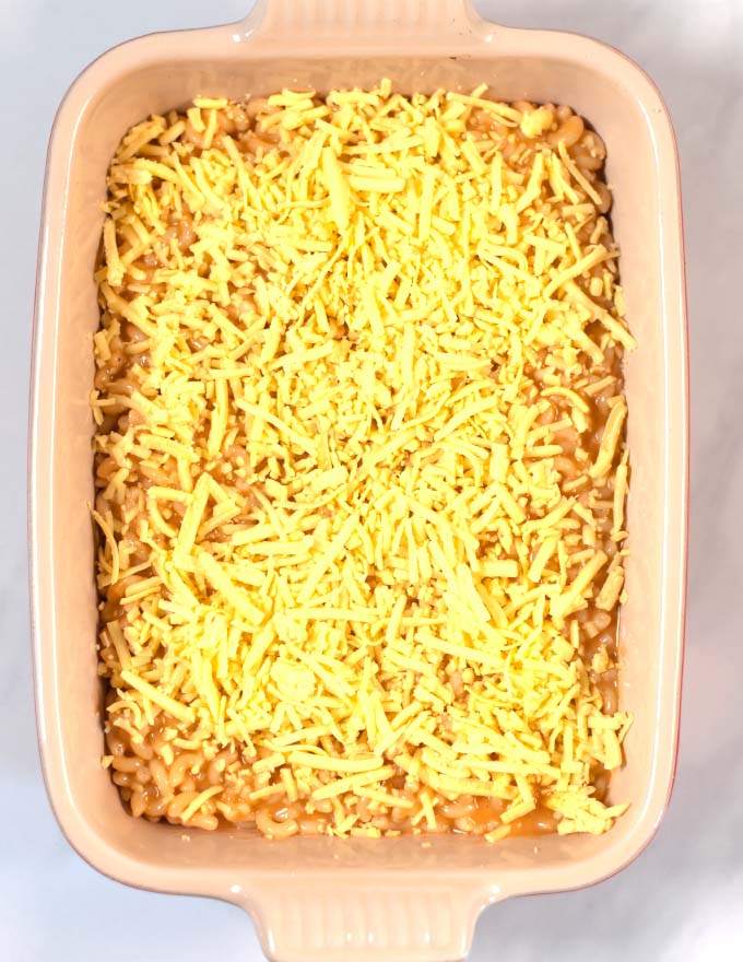 A baking dish with BBQ Mac and Cheese covered with vegan cheese before baking.