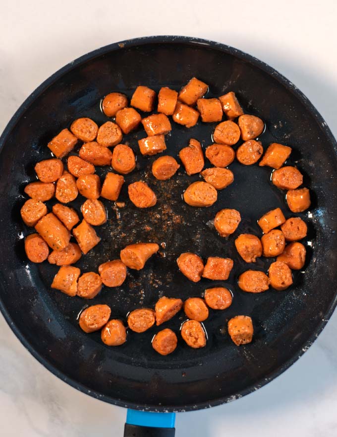 Sausage bits are browned in a pan.