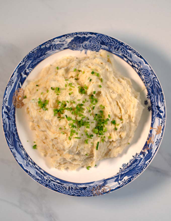 A top view of a large serving plate with mashed potatoes and cauliflower.