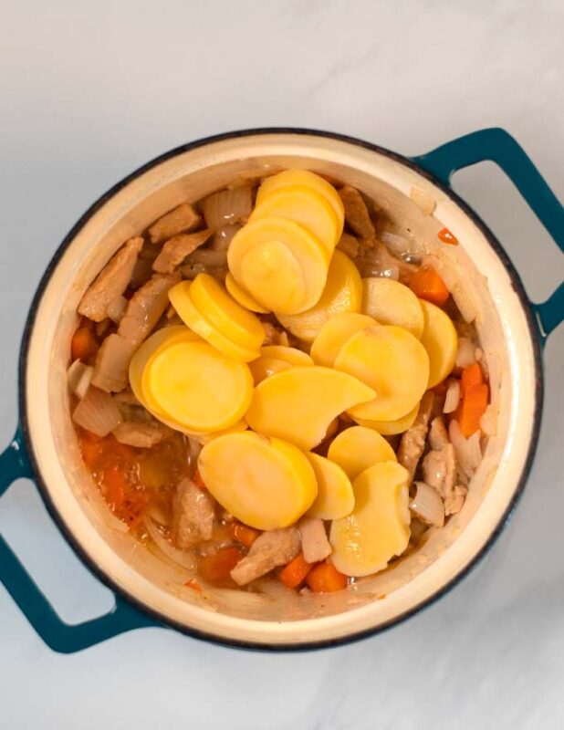 Slices potatoes are added to the curry pot.