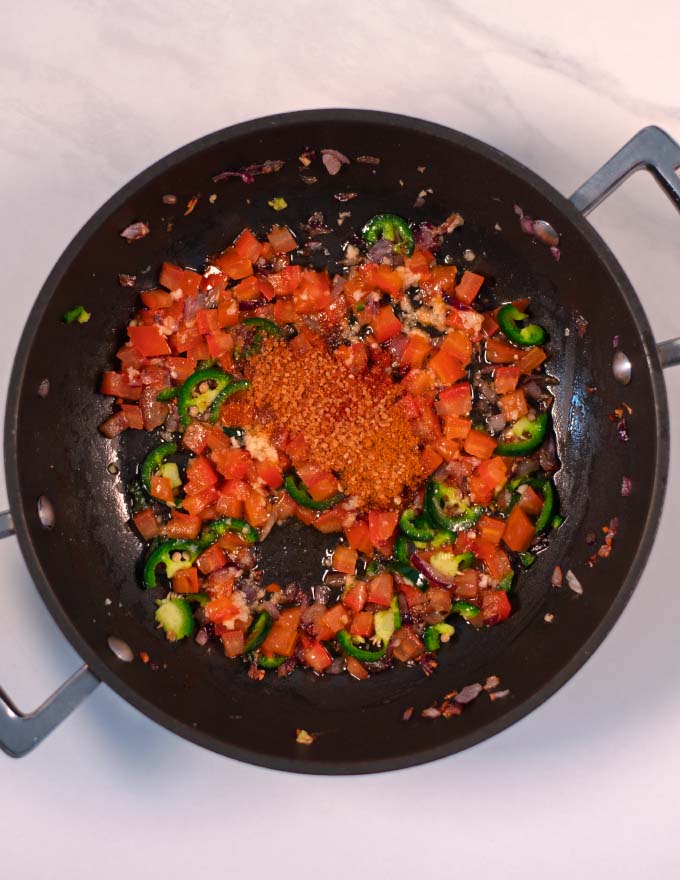 Spices are mixed with the vegetables in the pan.