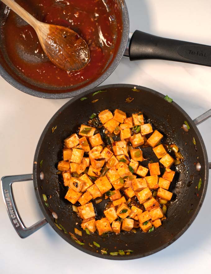 A pan with roasted and maridnated tofu with another pan of Filipino Barbecue Sauce in the background.