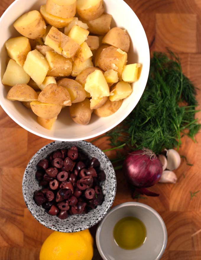 Ingredients needed to make Greek Lemon Potato Salad collected on a board.