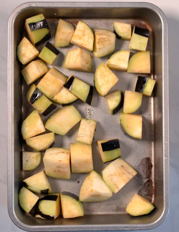 Olive oil coated eggplant bits in a baking dish.