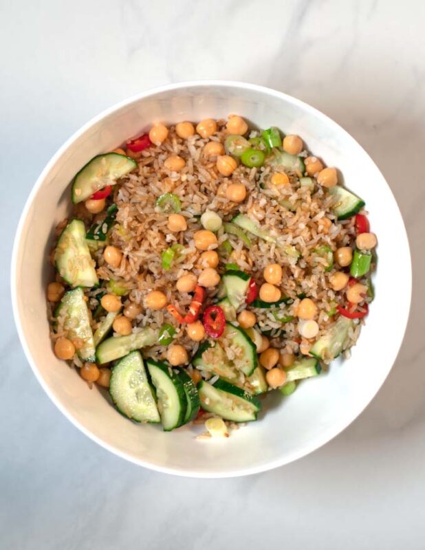 Mixed rice and salad ingredients in a white mixing bowl.
