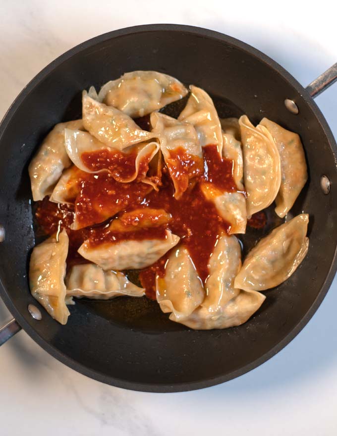Sambal sauce is given over the dumplings in the pan.