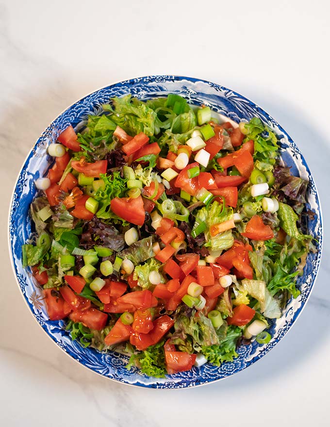 A large serving plate with green salad and vegetables.