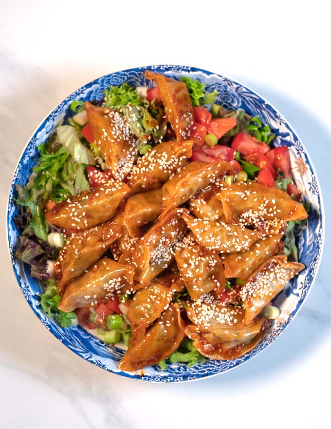 Sambal sauce covered dumplings are given over the salad and vegetables.