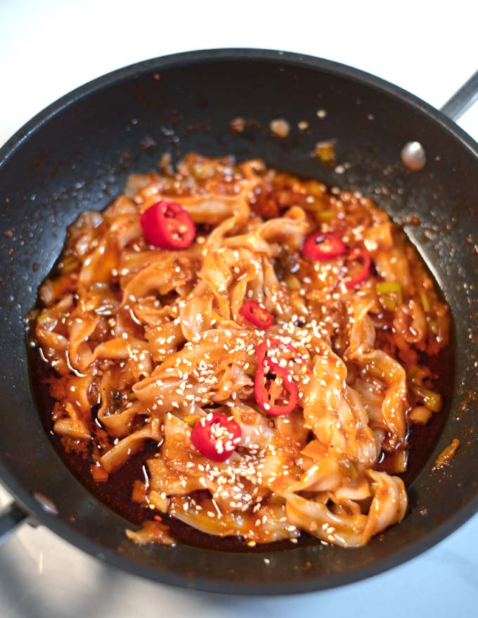 Closeup of Szechuan Noodles garnished with sesame seeds and chili.