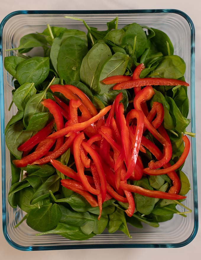 Spinach and sliced bell pepper are added to the baking dish