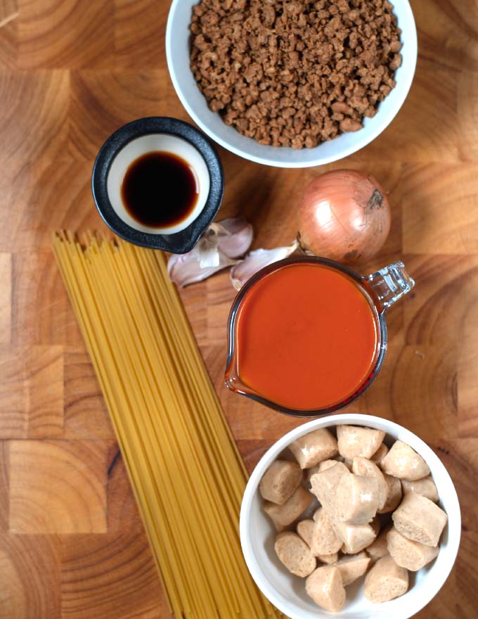 Ingredients needed to make Filipino Spaghetti collected on a board.