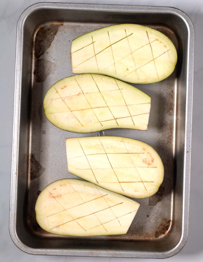 Hatched eggplant halves in a baking tray.