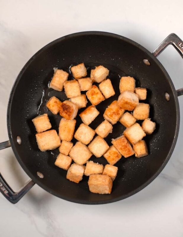 Crispy fried tofu cubes in a pan.
