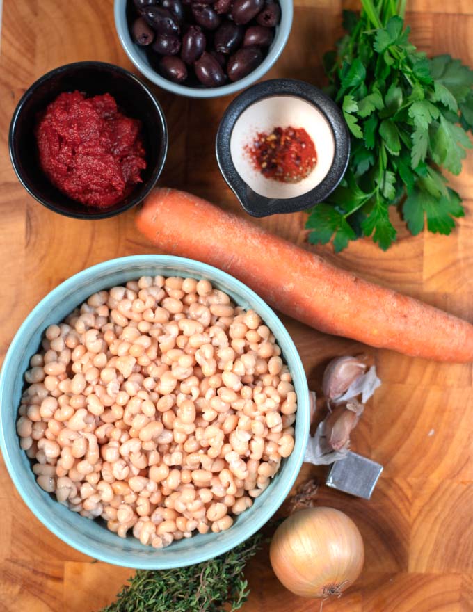 Ingredients needed to make Fasolada collected on a wooden board.